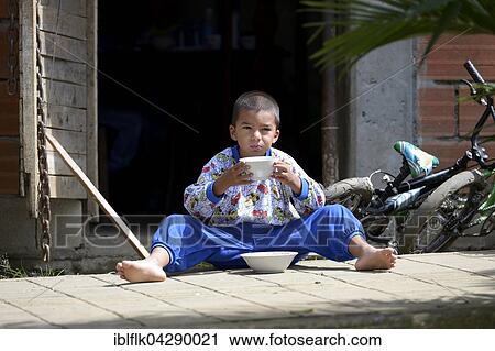 Boy sitting on ground while eating, Comuna 8 slum, Medellin, Antioquia Department, Colombia, South America View Large Photo Image Stock Image - Boy sitting on ground while eating, Comuna 8 slum, Medellin, Antioquia Department, Colombia, South America. Fotosearch