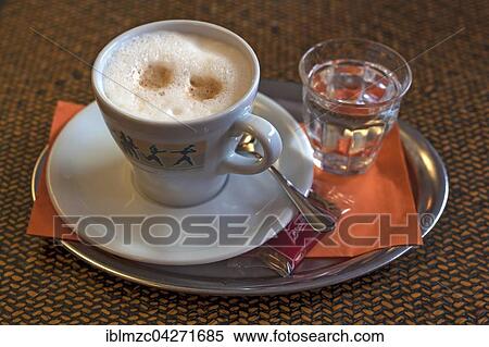 Cappuccino with a glass of water, on a tray View Large Photo Image Stock Photography - Cappuccino with a glass of water, on a tray. Fotosearch