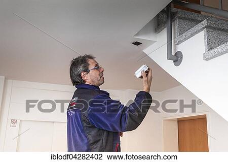 Stock Image - Caretaker with smoke detector in a stairwell, Dusseldorf, North Rhine-Westphalia, Germany, Europe. Fotosearch