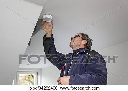 Stock Photograph - Caretaker with smoke detector in a stairwell, Dusseldorf, North Rhine-Westphalia, Germany, Europe. Fotosearch