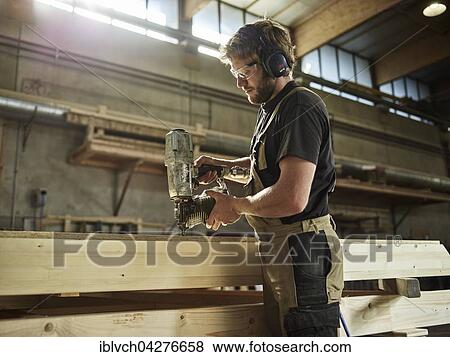 Carpenter nailing chipboard to a wooden beam, nail gun, timber frame construction, Austria, Europe View Large Photo Image Stock Photo - Carpenter nailing chipboard to a wooden beam, nail gun, timber frame construction, Austria, Europe. Fotosearch