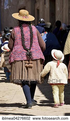 Stock Image - Child holding onto the coattails of its mother, typical hairstyle of the Indios, pigtail, in Potosi, Bolivia, South America. Fotosearch