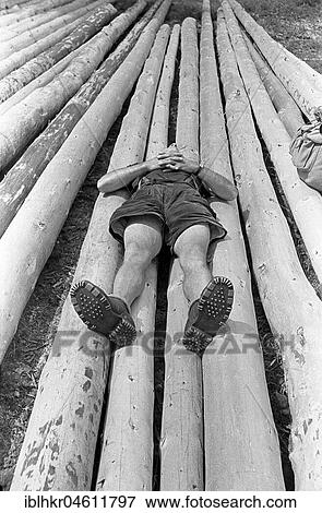 Stock Photo - Child lying on felled tree trunks and resting, around 1950, near Freiburg, Germany, Europe. Fotosearch