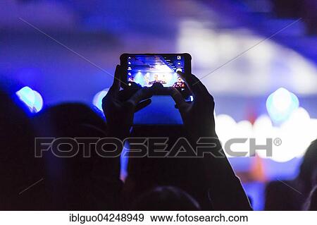 Concert-goer taking photo with iPhone View Large Photo Image Stock Photo - Concert-goer taking photo with iPhone. Fotosearch
