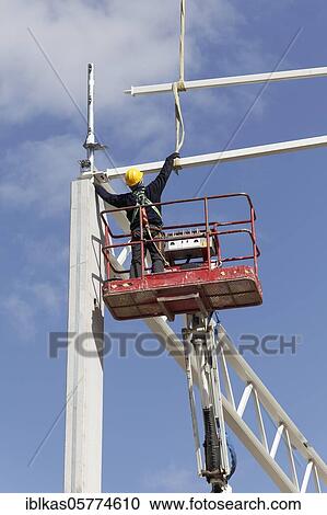 Stock Image - Construction worker on working platform, assembling the roof construction of a logistics hall, Duisburg, North Rhine-Westphalia, Germany, Europe. Fotosearch