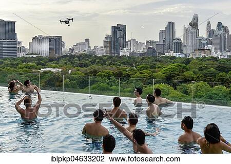 Stock Image - DJI Inspire 1 drone flies over Swimminpgool, in the background Skyline of Bangkok, Thailand, Asia. Fotosearch