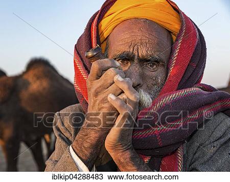 Stock Image - Elderly Rajasthani man with an turban smoking a hash pipe, Pushkar, Rajasthan, India, Asia. Fotosearch