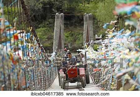 Farmer drives with a tractor over a suspension bridge decorated with prayer flags, Jiaju Village, autonomous district Garzê of the Tibetans, Sichuan, China, Asia View Large Photo Image Stock Photography - Farmer drives with a tractor over a suspension bridge decorated with prayer flags, Jiaju Village, autonomous district Garzê of the Tibetans, Sichuan, China, Asia. Fotosearch