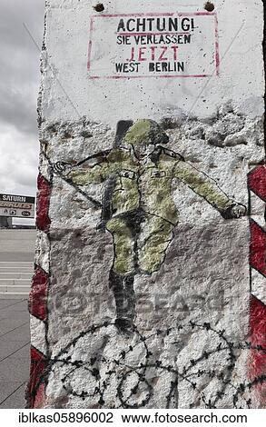 Stock Image - GDR border guard jumps over barbed wire to the West, graffito on a fragment of the Berlin Wall, Weimar, Thuringia, Germany, Europe. Fotosearch
