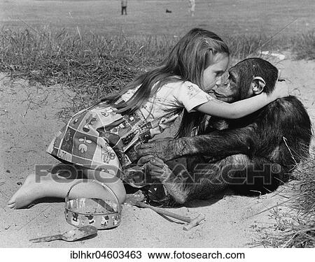 Stock Image - Girl kisses chimpanzee on the beach, England, Great Britain. Fotosearch