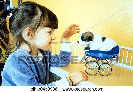 Stock Image - Girl playing with little puppy, England, Great Britain. Fotosearch