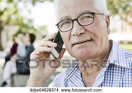 Grey-haired senior with glasses talking on the phone with his smartphone, Germany, Europe View Large Photo Image Picture - Grey-haired senior with glasses talking on the phone with his smartphone, Germany, Europe. Fotosearch