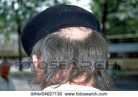 Stock Photography - Halbglatze looks out from under a cap, Berlin, Germany, Europe. Fotosearch
