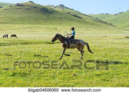 Stock Image - Kyrgyz boy riding his horse, Song Kol Lake, Naryn province, Kyrgyzstan, Central Asia, Asia. Fotosearch