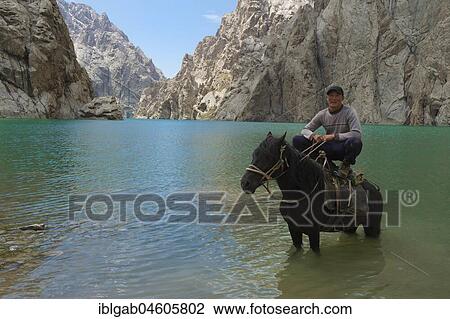 Stock Image - Kyrgyz showing his agility on his horse in Köl-Suu lake, Kurumduk valley, Naryn province, Kyrgyzstan, Asia. Fotosearch