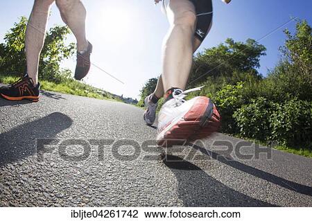 Stock Image - Legs, jogging shoes, joggers on asphalt track, Germany, Europe. Fotosearch