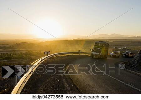 Stock Photo - Loaded truck on curvy road in Dades Valley at sunset, Ouarzazate, Morocco, Africa. Fotosearch