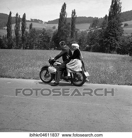 Stock Photo - Man and daughter riding a motorbike on a country road, around 1950, near Freiburg, Germany, Europe. Fotosearch