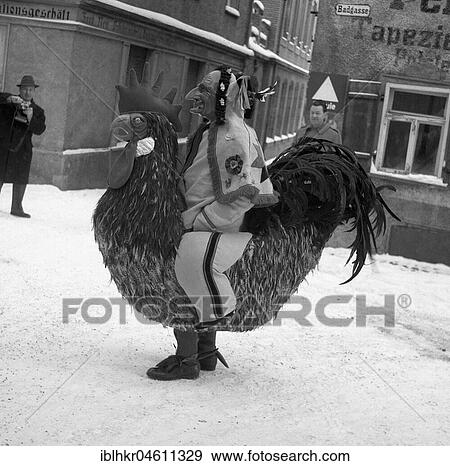 Stock Photo - Man dressed as a cock walks through the snow-covered streets of Freiburg, carnival, ca. 1955, Freiburg, Germany, Europe. Fotosearch