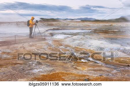 Man in yellow jacket with photo tripod, photo backpack and camera standing in the steaming red high temperature area Hverarönd with solfatars and fumaroles, Skútustaðir, Norðurland eystra, Iceland, Europe View Large Photo Image Stock Photograph - Man in yellow jacket with photo tripod, photo backpack and camera standing in the steaming red high temperature area Hverarönd with solfatars and fumaroles, Skútustaðir, Norðurland eystra, Iceland, Europe. Fotosearch