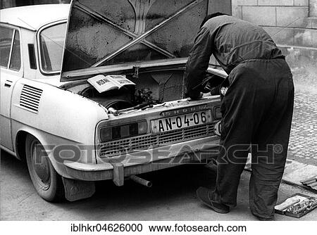 Stock Image - Man repairing car after instruction ca. 1970s, exact place unknown, Czech Republic, Europe. Fotosearch