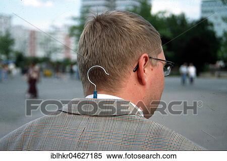 Stock Photography - Man with coat hanger under jacket, Berlin, Germany, Europe. Fotosearch