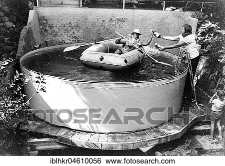 Stock Photograph - Man with lifejacket in inflatable dinghy in paddling pool, Mexico City, Mexico, Central America. Fotosearch
