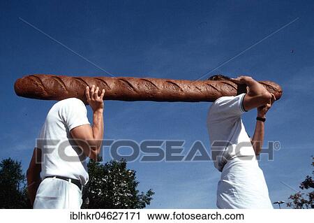 Stock Image - Men carry giant baguette, Berlin, Germany, Europe. Fotosearch