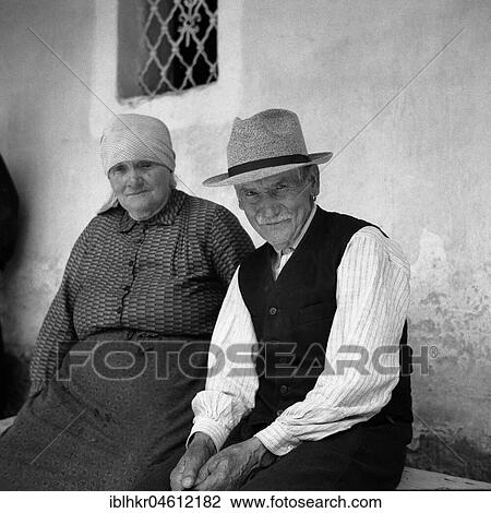 Stock Image - Old couple sitting on a bench and smiling at the camera, around Freiburg from 1945 to 1955. Fotosearch