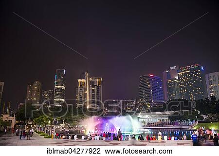 Stock Image - People watching light show, water fountain, Lake Symphony, city park, skyscrapers, City Centre, Kuala Lumpur, Malaysia, Asia. Fotosearch