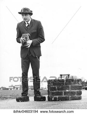 Picture - Photographer, man with suitcase, shoes and camera made of bricks, England, Great Britain. Fotosearch