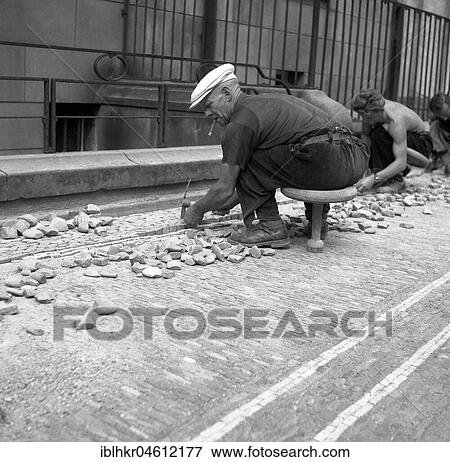 Stock Photo - Road workers paving a road with natural stones, Freiburg ca. 1945 to 1955. Fotosearch