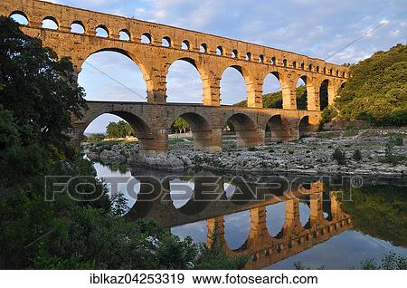 Roman aqueduct Pont du Gard reflected in the Gardon river in the evening, Remoulins, Provence, Southern France, France, Europe View Large Photo Image Stock Photo - Roman aqueduct Pont du Gard reflected in the Gardon river in the evening, Remoulins, Provence, Southern France, France, Europe. Fotosearch