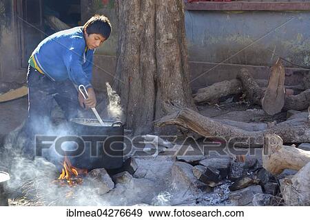 Stock Photo - Schoolboy preparing breakfast on an open fire, boarding school in Potosi, Bolivia, South America. Fotosearch