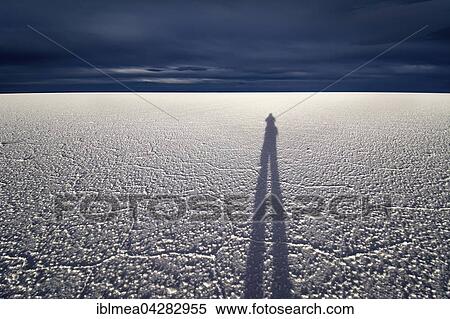 Shadow of man on salt flat in front of dark clouds, Salar de Uyuni, Altiplano, Bolivia, South America View Large Photo Image Stock Photography - Shadow of man on salt flat in front of dark clouds, Salar de Uyuni, Altiplano, Bolivia, South America. Fotosearch