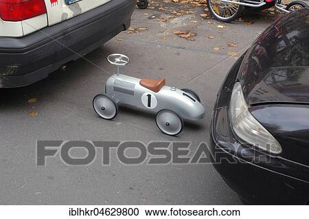 Stock Image - Size difference, small toy car on the parking lot, Berlin, Germany, Europe. Fotosearch