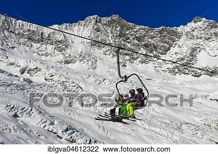 Skiers on a chairlift in front of the Feegletscher and the peaks Dom and Lenzspitze, Mischabel Group, Saas-Fee ski area, Valais, Switzerland, Europe View Large Photo Image Stock Image - Skiers on a chairlift in front of the Feegletscher and the peaks Dom and Lenzspitze, Mischabel Group, Saas-Fee ski area, Valais, Switzerland, Europe. Fotosearch