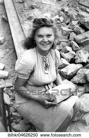 Stock Image - Smiling Debris Woman with Stone, ca. 1945/1946, Leipzig, Germany, Europe. Fotosearch