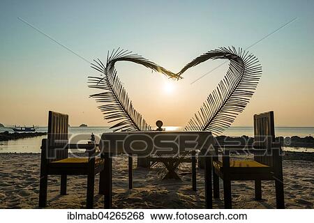 Table on the beach with a heart made of palm fronds, sunset, Koh Samui island, Gulf of Thailand, Thailand, Asia View Large Photo Image Stock Photo - Table on the beach with a heart made of palm fronds, sunset, Koh Samui island, Gulf of Thailand, Thailand, Asia. Fotosearch