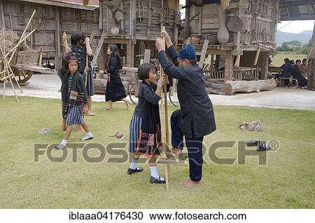 Stock Image - Tai Dam children walking on bamboo stilts, Loei province, Thailand, Asia. Fotosearch