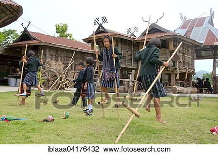Stock Image - Tai Dam children walking on bamboo stilts, Loei province, Thailand, Asia. Fotosearch