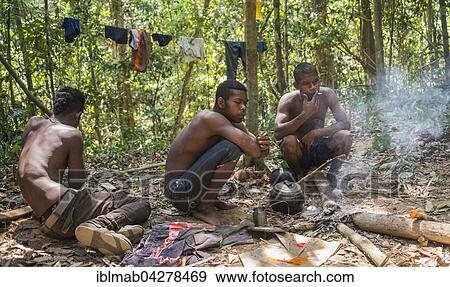 Stock Photo - Three young aboriginal Orang Asil men sitting on the ground in the jungle, smoking, indigenous culture, tropical rainforest, Taman Negara, Malaysia, Asia. Fotosearch
