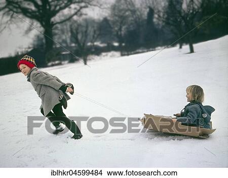 Two children ride on sledges made of cardboard, England, Great Britain View Large Photo Image Picture - Two children ride on sledges made of cardboard, England, Great Britain. Fotosearch