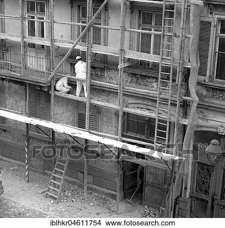 Two construction workers renovate the facade of a house around 1950, Freiburg, Germany, Europe View Large Photo Image Picture - Two construction workers renovate the facade of a house around 1950, Freiburg, Germany, Europe. Fotosearch