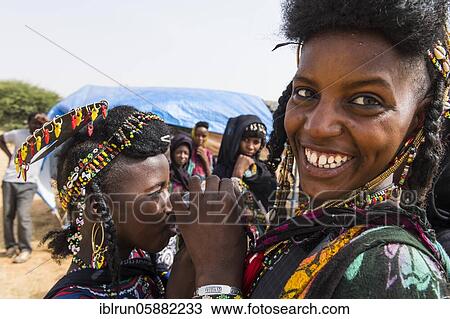 Stock Image - Two girls sharing a waterbag, Gerewol festival, courtship ritual competition among the Woodaabe Fula people, Niger, Africa. Fotosearch