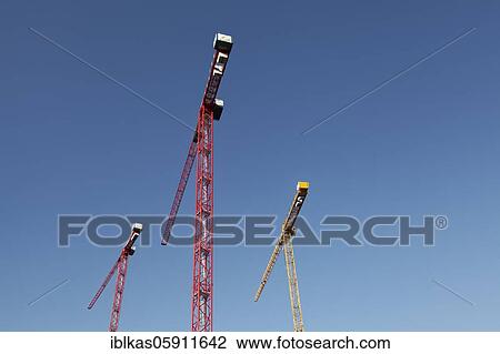 Two red construction cranes and a yellow construction crane in front of a blue sky, Germany, Europe View Large Photo Image Stock Image - Two red construction cranes and a yellow construction crane in front of a blue sky, Germany, Europe. Fotosearch