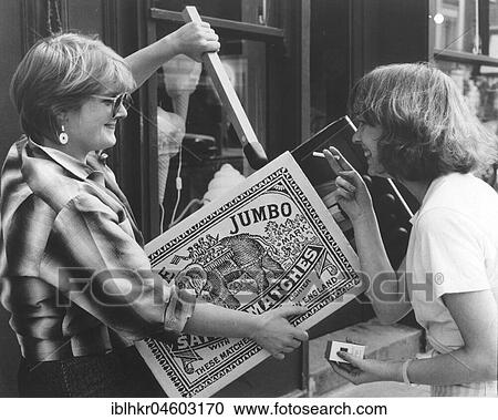 Stock Image - Two women with large matchbox, England, Great Britain. Fotosearch
