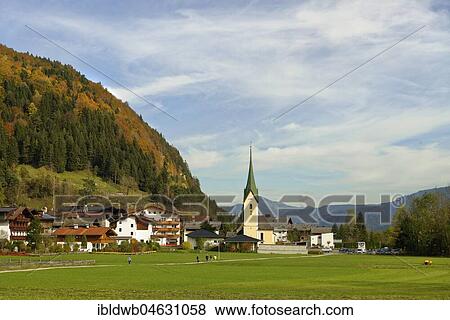 Stock Photo - View of village with parish church St. Johannes the Baptist in autumn, Walchsee, Kaiserwinkl, Tyrol, Austria, Europe. Fotosearch
