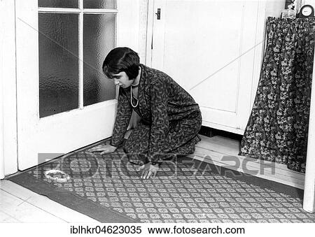 Stock Photography - Woman kneels on the ground in front of an apple peel ca. 1927 superstition, tradition supplied, exact place unknown, Germany, Europe. Fotosearch