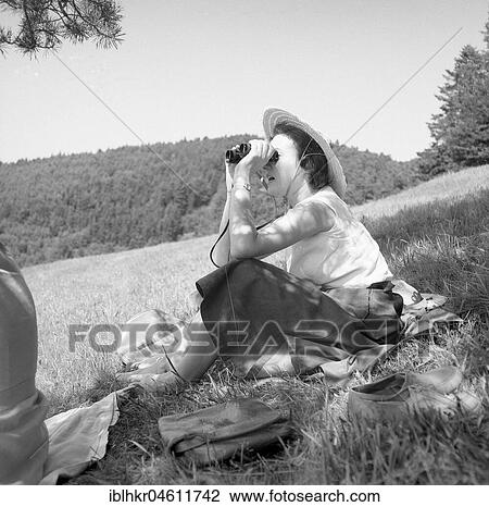 Woman sitting in nature looking through binoculars around 1950, near Freiburg, Germany, Europe View Large Photo Image Stock Image - Woman sitting in nature looking through binoculars around 1950, near Freiburg, Germany, Europe. Fotosearch
